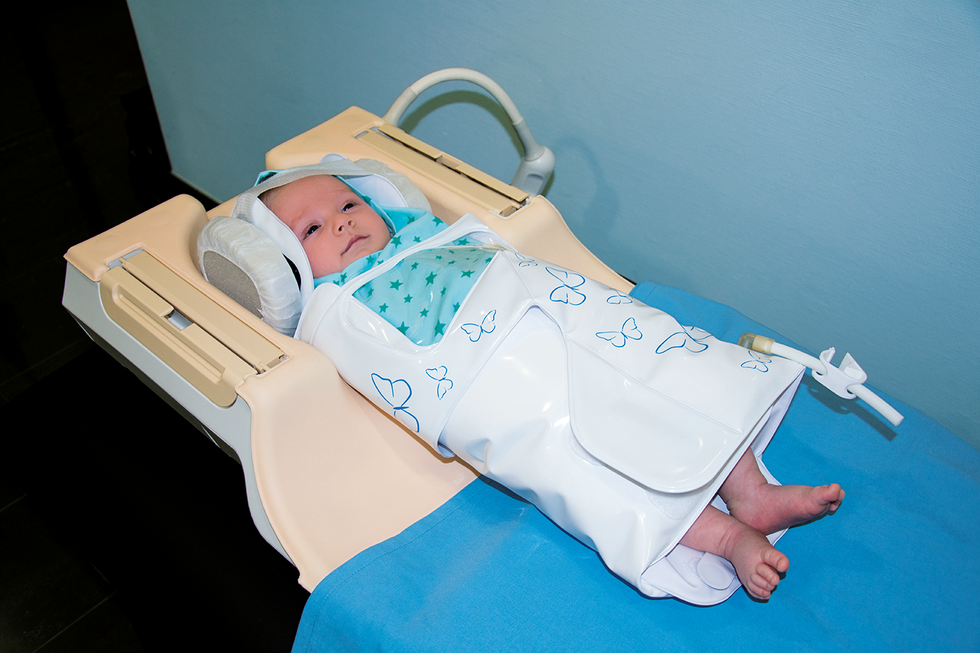 Newborn wrapped in BabyFix Cocoon lying in MRI head-coil